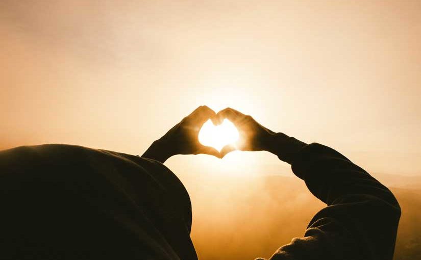 Hands in shape of heart in front of sun