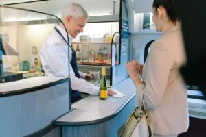 Cafe car attendee serving wine to train rider